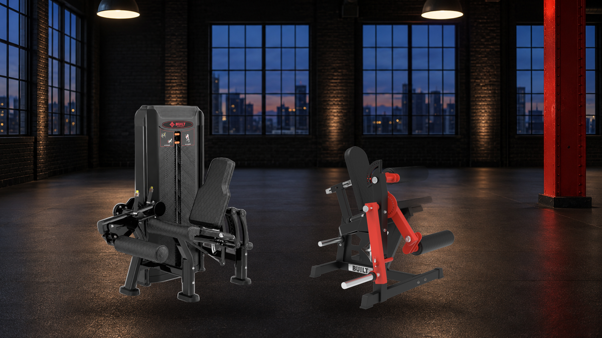 BUILT Strength Fractal Series Leg Extension and OG Series Plate Loaded Leg Extension Leg Curl in an industrial loft gym at dusk