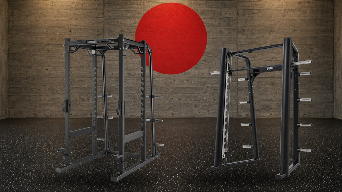 Precor Discovery Series power rack and BUILT Strength Foundation Series Smith Machine side by side in a concrete strength hall with a red circle on the wall